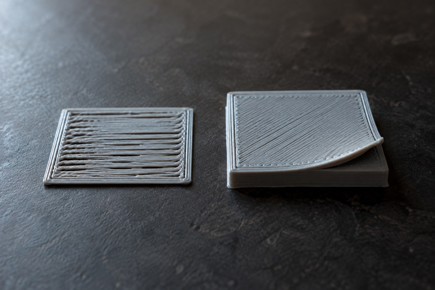 Illustration: Macro comparison of two square filament-print samples: one with uneven separated first-layer lines, one thicker square with a visibly lifted corner