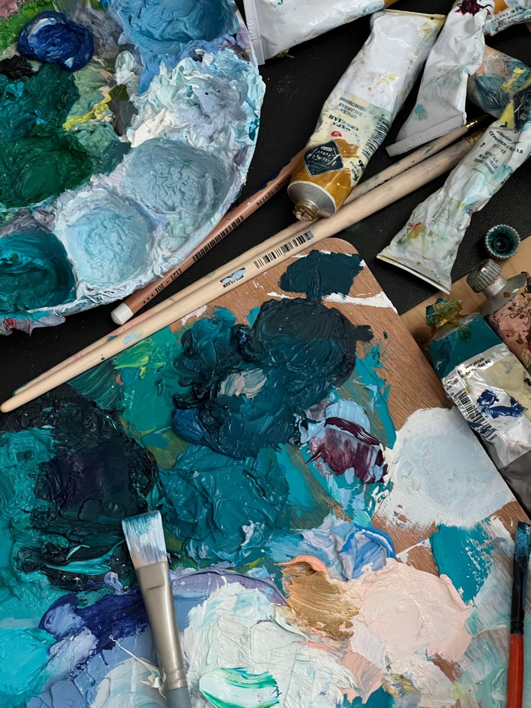 Mixed paint colours and brushes on a palette